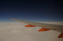 View out of aeroplane window of wing and clouds