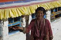 Monpa woman with typical headdress spinning prayer wheel, Tawang, Arunachal Pradesh, India 2005