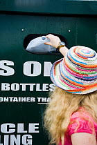 Woman putting plastic bottle into recycling bin in supermarket carpark, Shrewsbury, Shropshire, UK 2007 Model released