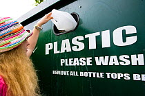 Woman putting plastic bottle into recycling unit in supermarket carpark, Shrewsbury, Shropshire, UK