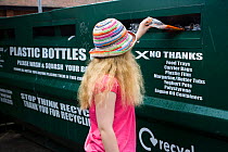 Woman putting plastic bottle into recycling unit in supermarket carpark, Shrewsbury, Shropshire, UK 2007 model released
