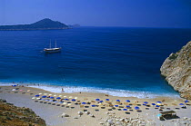 Kaputas beach with umbrellas and boat moored offshore, south coast nr Kas, Turkey