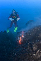 Diver Bud Turpin observes erupting pillow lava at ocean entry of Kilauea Volcano on Hawaii Island, Hawaii. Heat waves rising from the lava distort his image. Model released MR 381