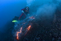 Diver Bud Turpin observes erupting pillow lava at ocean entry of Kilauea Volcano on Hawaii Island, Hawaii,  Heat waves rising from the lava distort his image. Model released MR 381