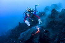 Diver Bud Turpin observes erupting pillow lava at ocean entry of Kilauea Volcano on Hawaii Island, Hawaii. Heat waves rising from the lava distort his image Model released MR 381