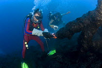 Diver Bud Turpin shapes erupting pillow lava by hand to form underwater lava sculptures at ocean entry from Kilauea Volcano, Hawaii Island, while son Shane Turpin shoots video  Model released MR 381,...