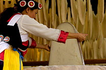 Naxi woman in traditional dress with the seven-starred cape stretching silk cocoons to be dried later and then spun. Lijiang Yunnan Province, China   2006
