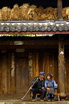 Naxi wom with man smoking long-stemmed bamboo pipe, Lijiang Yunnan Province, China 2006