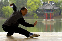 Chinese man doing Tai Chi excercises at Black Dragon Pool with One-Cent Pavilion in background,Lijiang, Yunnan Province, China 2006