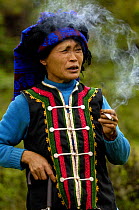 Colourful belt Yi woman smoking cigarette. From the mountains near Liuku, Nujiang Prefecture, Yunnan Province, China 2006