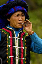 Colourful belt Yi woman smoking cigarette. From the mountains near Liuku, Nujiang Prefecture, Yunnan Province, China 2006