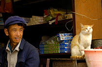Hani man sitting in his store with a cat, Yuanyang, Honghe Prefecture, Yunnan Province,  2006