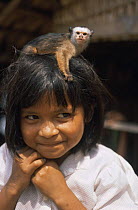 Satare indian girl with tame Satare maues marmoset {Callithrix mauesi satare} on her head, Amazonia, Brazil