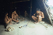 Matis hunters making traditional arrows around hut, Amazonia, Brazil