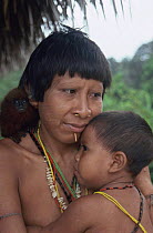 Matis woman holding child, facial decorations to mimic jaguar, Amazonia, Brazil