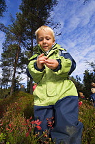 Boy in a Norwegian naturbarnehage (nature nursery) examining a Snail, Trondheim, Norway, 2006