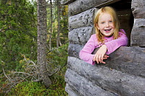Girl in a naturbarnehage (nature nursery) looking out of log cabin in the woods, Trondheim, Norway 2006
