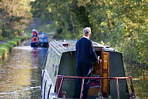 Man driving a canal boat on the Monmouthshire and Brecon Canal at Talybont on Usk, Brecon Beacons, Wales