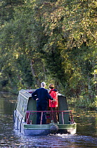 Couple driving a canal boat on the Monmouthshire and Brecon Canal at Talybont on Usk, Brecon Beacons, Wales