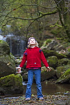 Girl throwing leaves in air in Autumnal woodland, Brecon Beacons, Wales