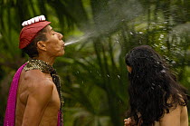 Colorado or Tsáchila Indian Shaman performs a cleansing ceremony by spraying a concoction of alcohol and medicinal herbs over his 'patient'.  Santo Domingo de los Colorados. Coastal ECUADOR. South Am...