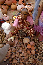 Woman selling pottery during Diwali festival, Bharatpur village. Rajasthan, India, October 2006