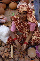 Woman selling pottery in the market during Diwali Festival, Bharatpur village, Rajasthan, India, 2006