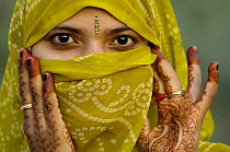Hindu Woman looking out from inside her veil with hand tatoos painted for the Diwali festival, (only married women wear veils) near Bharatpur. Rajasthan, India 2006,