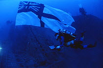 Diver raising the Naval Ensign over the wreck of HMS Manchester, WWII British Cruiser that was scuttled in the Mediterranean Sea after torpedo damage in 1942