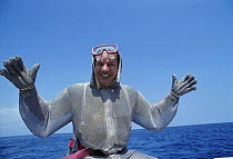 Underwater photographer Jeff Rotman, dressed in chain mail protective dive suit, preparing to photograph sharks. Bahamas, Caribbean, Atlantic Ocean. Model released.