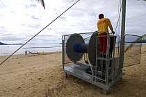 Lifeguard using machine on beach, towing ropes for stinger-resistant enclosure, Queensland, Australia  2006