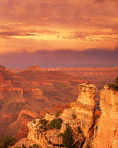 Sunset at Yaki Point on the South Rim with stratified rim rocks and minute storm clouds inside the canyon below, Grand Canyon National Park, Arizona, USA.