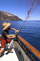 Firing chum slick into the water as bait for Great white shark cage-diving, Guadalupe Island, Mexico (North Pacific)