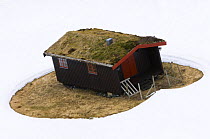 The case for house insulation - Cabin with melted snow around it illustrating the need for heat insulation, Norway 2007