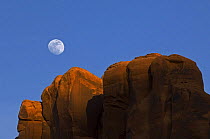 Red sandstone cliffs at sunset with moon in the sky, Monument Valley Navajo Tribal Park, Arizona, USA May 2007
