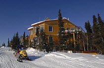 Blachford Lake Lodge, an environmentally friendly and remote fly-in lodge, and man on skidoo, Northwest Territories, Canada. March 2007