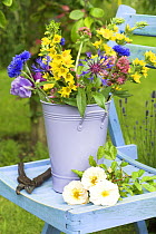 Summer Garden scene with cut flowers in bucket on garden seat, UK