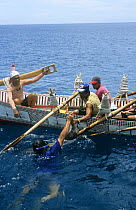 Tao tribe skin-diver hands catch of reef fish netted using Mitawah technique to oarsman of ten-man hand-made traditional plankboat or Cinedkeran, Orchid Island, Taiwan. 2007
