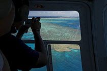 Silhouette of tourist taking a photo of the Great Barrier Reef from a Helicopter. Queensland, Australia