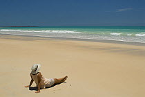 Woman relaxing on Broome's Cable Beach, looking out to sea, Western Australia