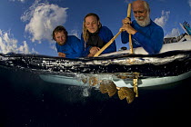 Scientists on the Undersea Explorer research vessel testing a coconut rattle to attract sharks. Queensland, Australia.  John Rumney