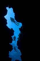 Divers silhouetted at entrance to underwater cave, Queensland, Australia