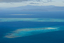 Aerial view of a Sand Cay on the Great Barrier Reef, with Australia's coastline (Cairns area) in the background. Queensland, Australia