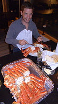 Man eating dressed Giant red king crab {Paralithodes camtschaticus} in restaurant, Kirkiness, Norway