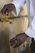 African scientist collecting water sample from tap, Gambia (Reconstruction) 2007