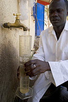 African scientist collecting water sample from tap, Gambia (Reconstruction) 2007