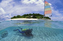 Split level of a diver and hobycat sailing boat in front of Club Paradise, Dimakya Island, Palawan, Philippines