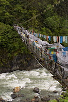 Rope bridge adorned with prayer flags, Yarlung Gorge, Tibet, May 07. 'Wild China' series Note - World's deepest gorge