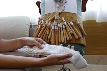 Woman holding lace cloth that she has made with lace bobbins in her workshop, Galicia, Spain