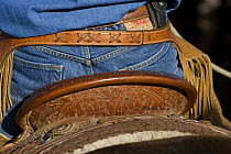 Detail of back of cowboy's saddle, jeans and chaps, Sombrero Ranch, Craig, Colorado, USA, model released